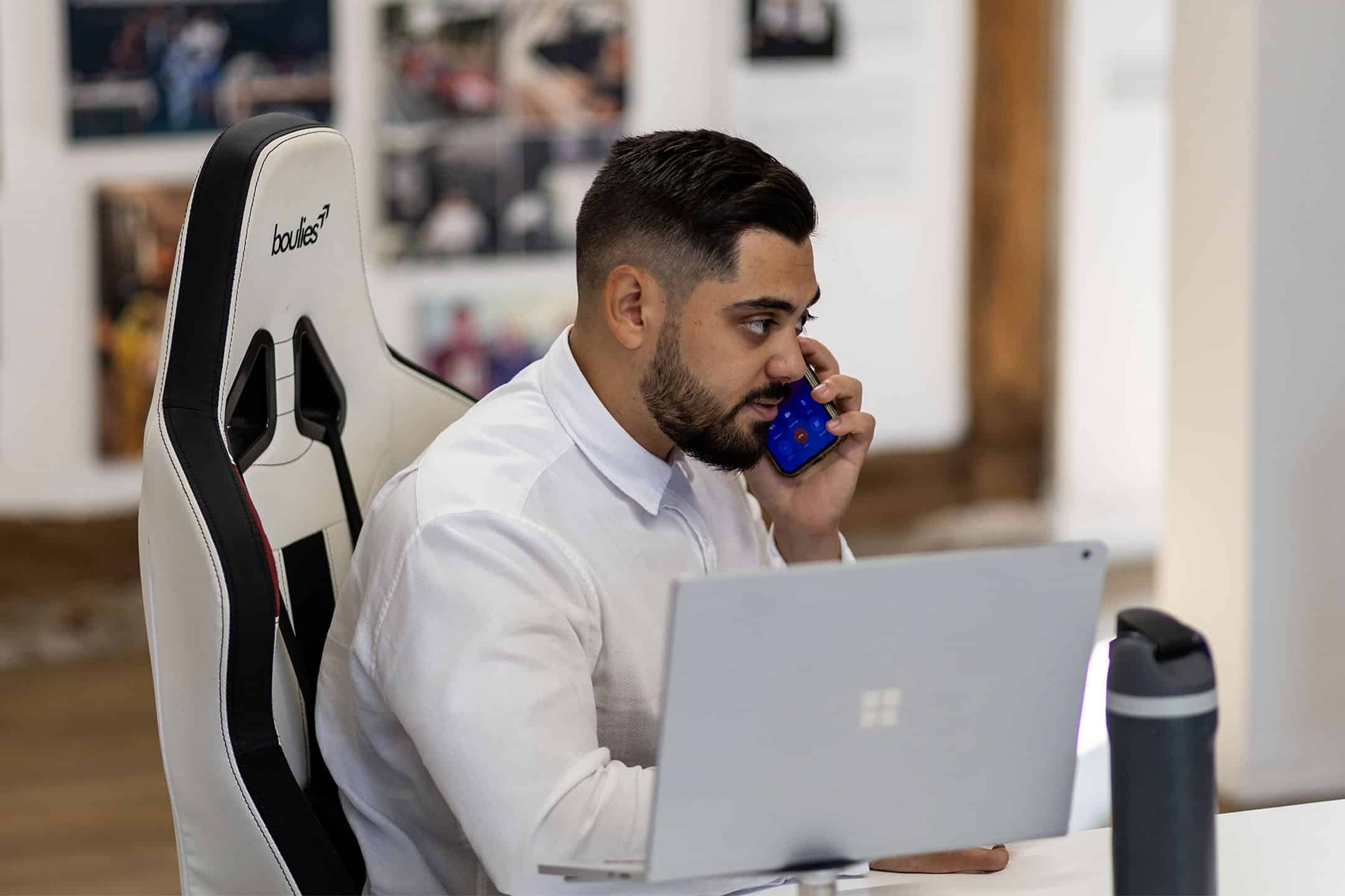 Man working at desk with laptop and mobile phone in office.
