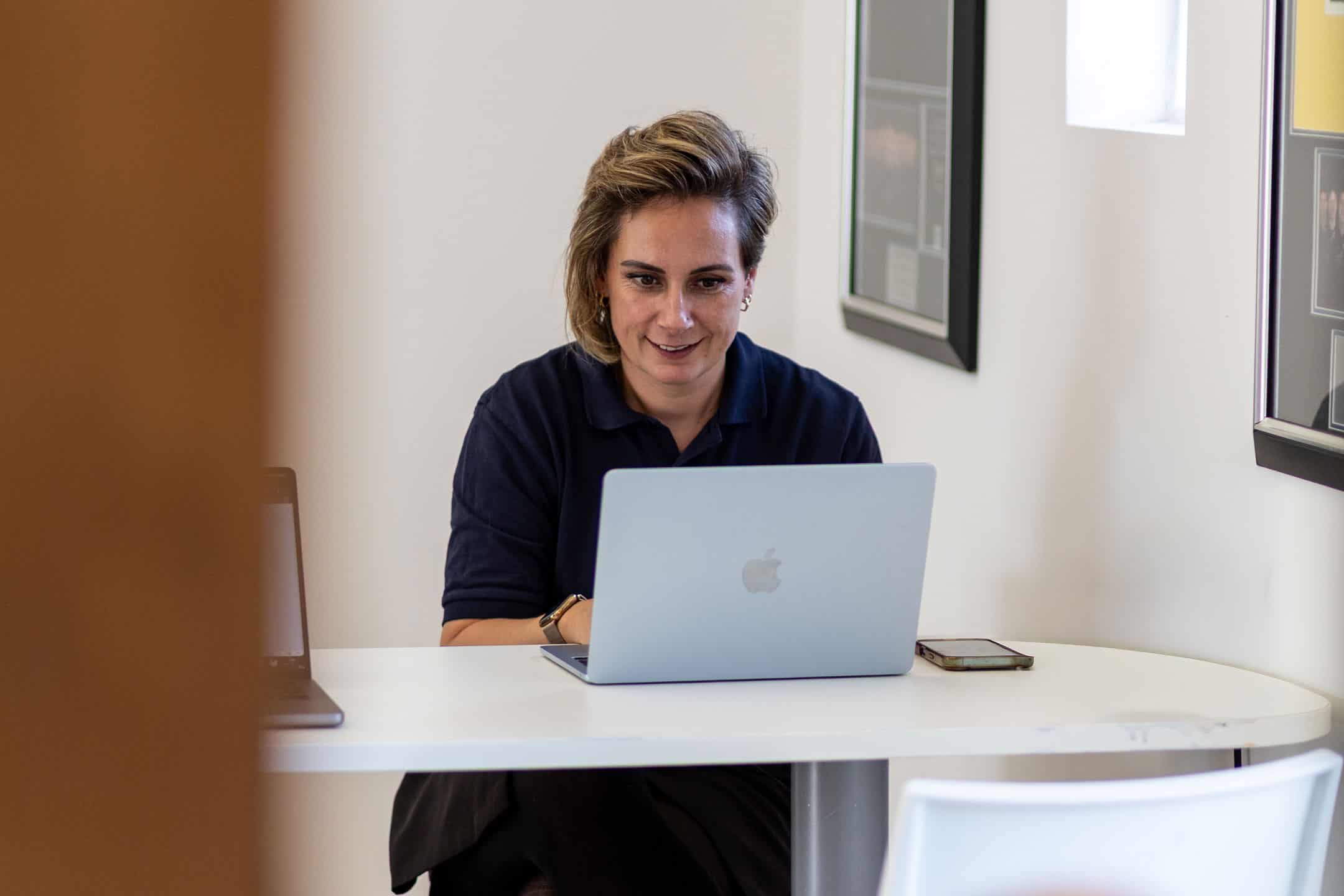 Woman working on a laptop in an office setting for device management.