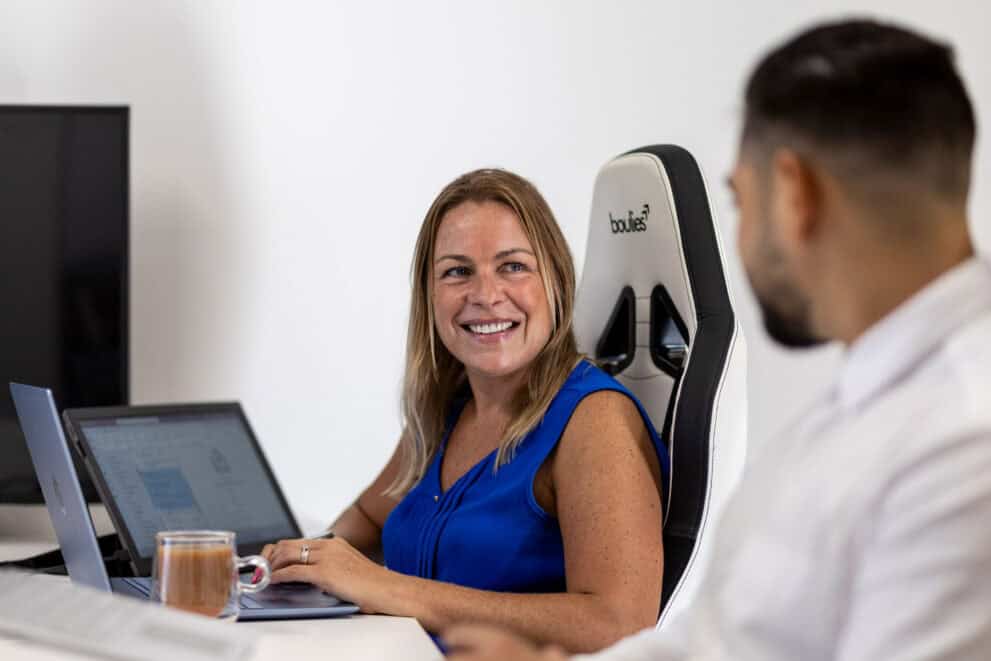 Woman smiling at her laptop during a business meeting.