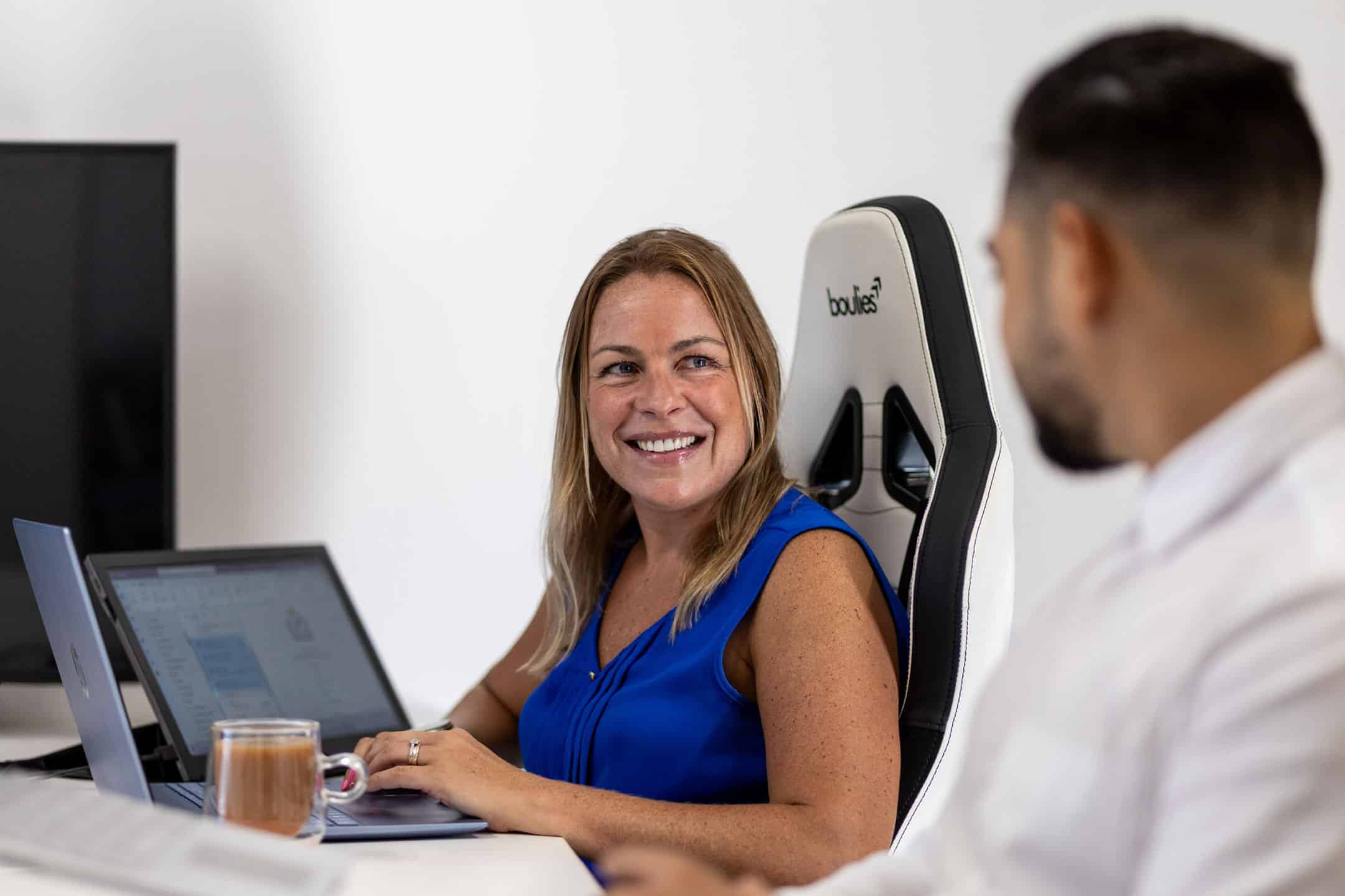 Woman smiling at her laptop during a business meeting.