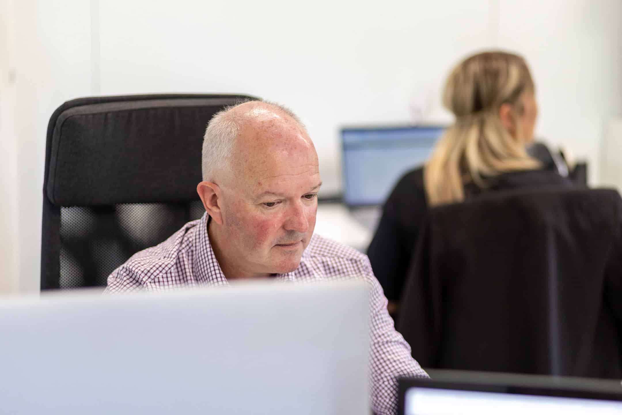 Office workers working at desks with computers in a modern workspace.