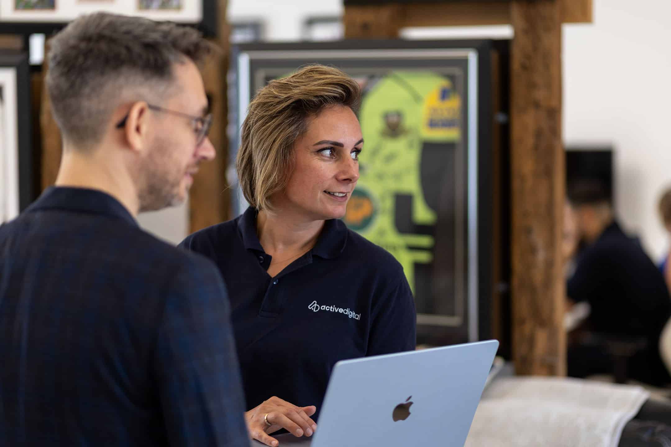 Active Digital staff assisting a customer with a laptop in a modern office.