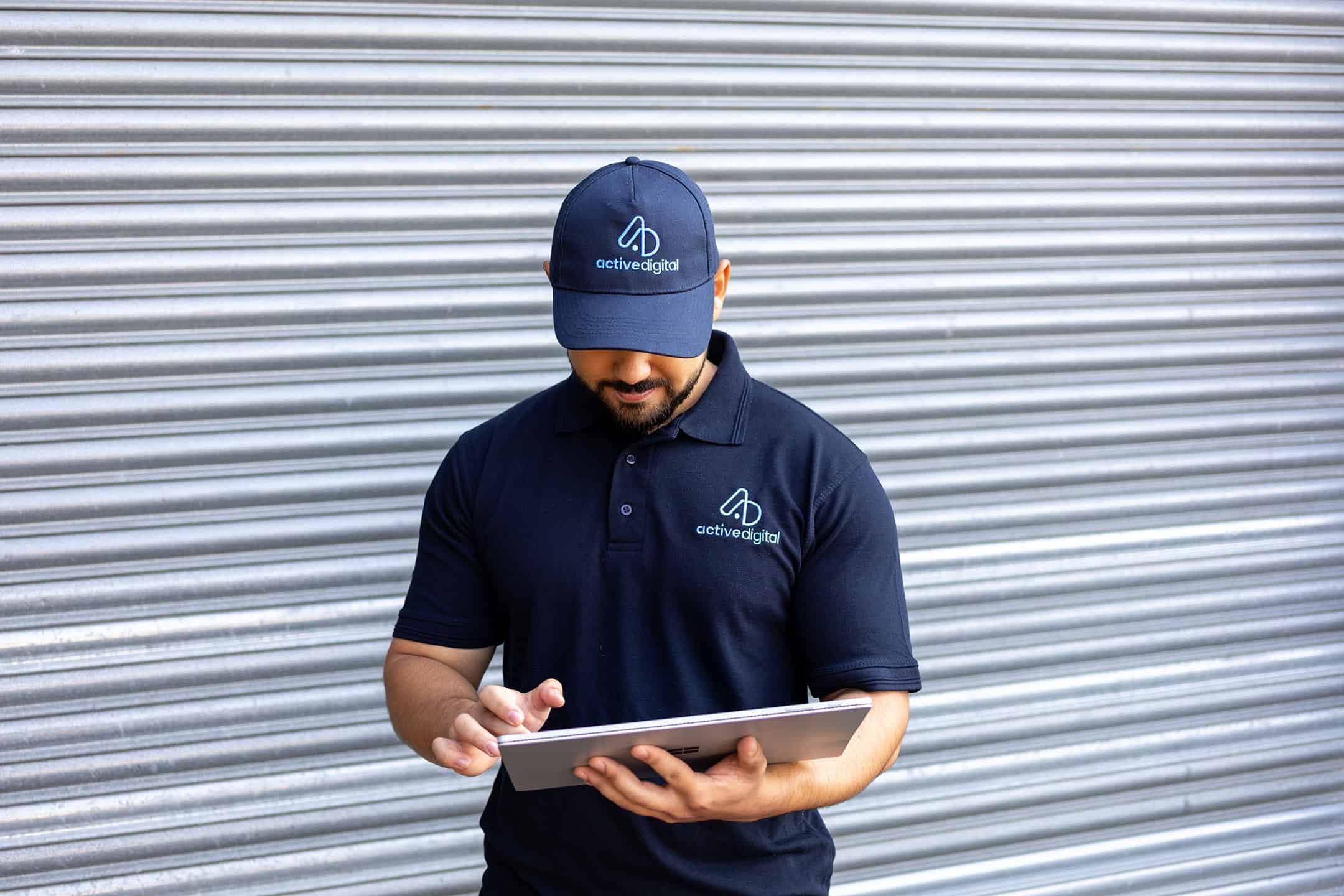 Service technician in uniform using a tablet in front of a metal shutter.