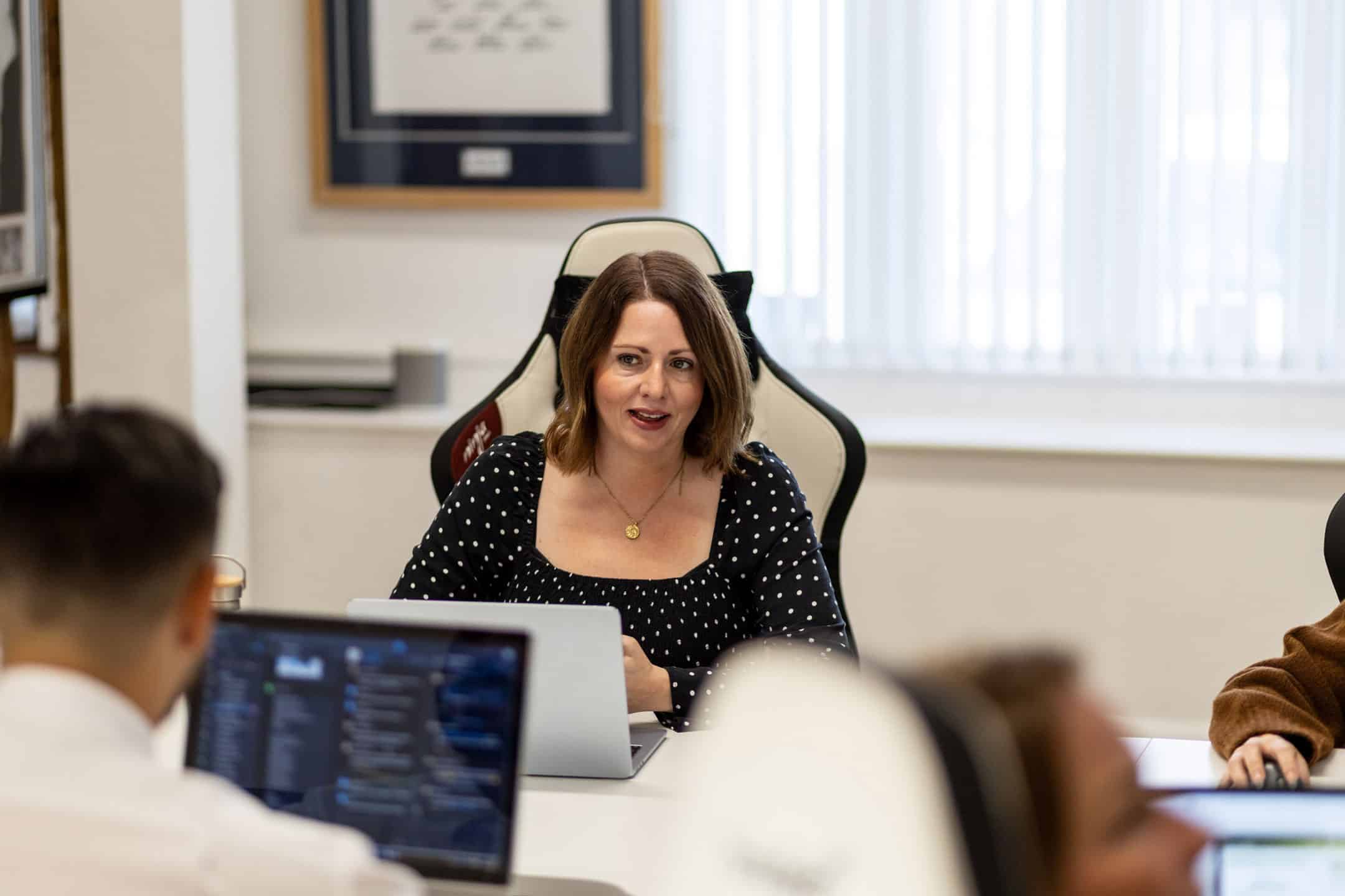 Woman leading a business meeting in an office setting with colleagues.