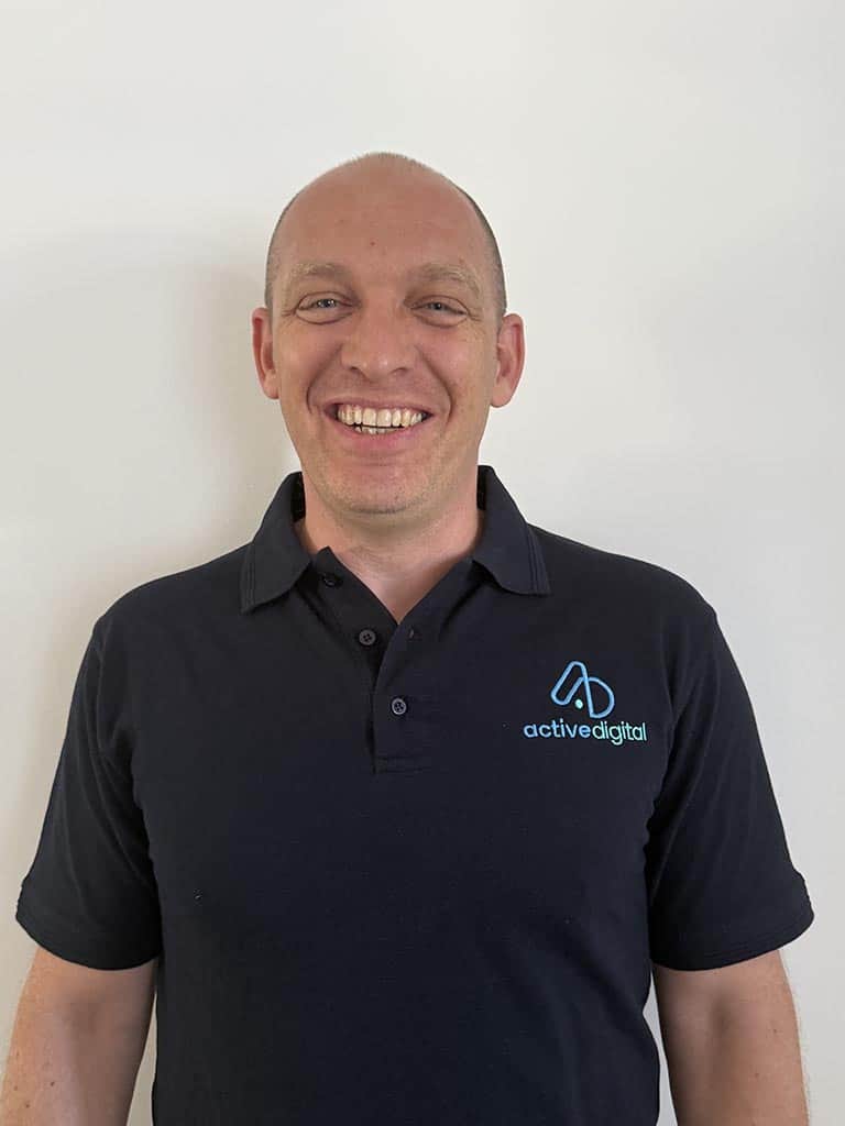 Smiling man in Active Digital polo shirt against white background.