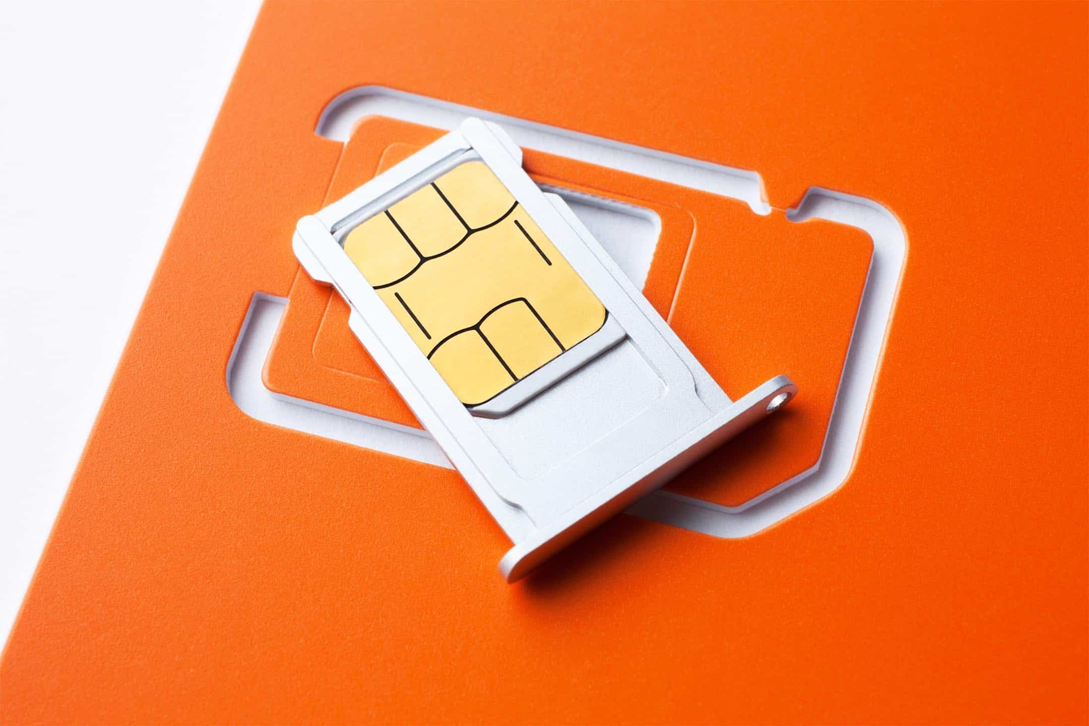 Close-up of a SIM card in a holder on an orange background.