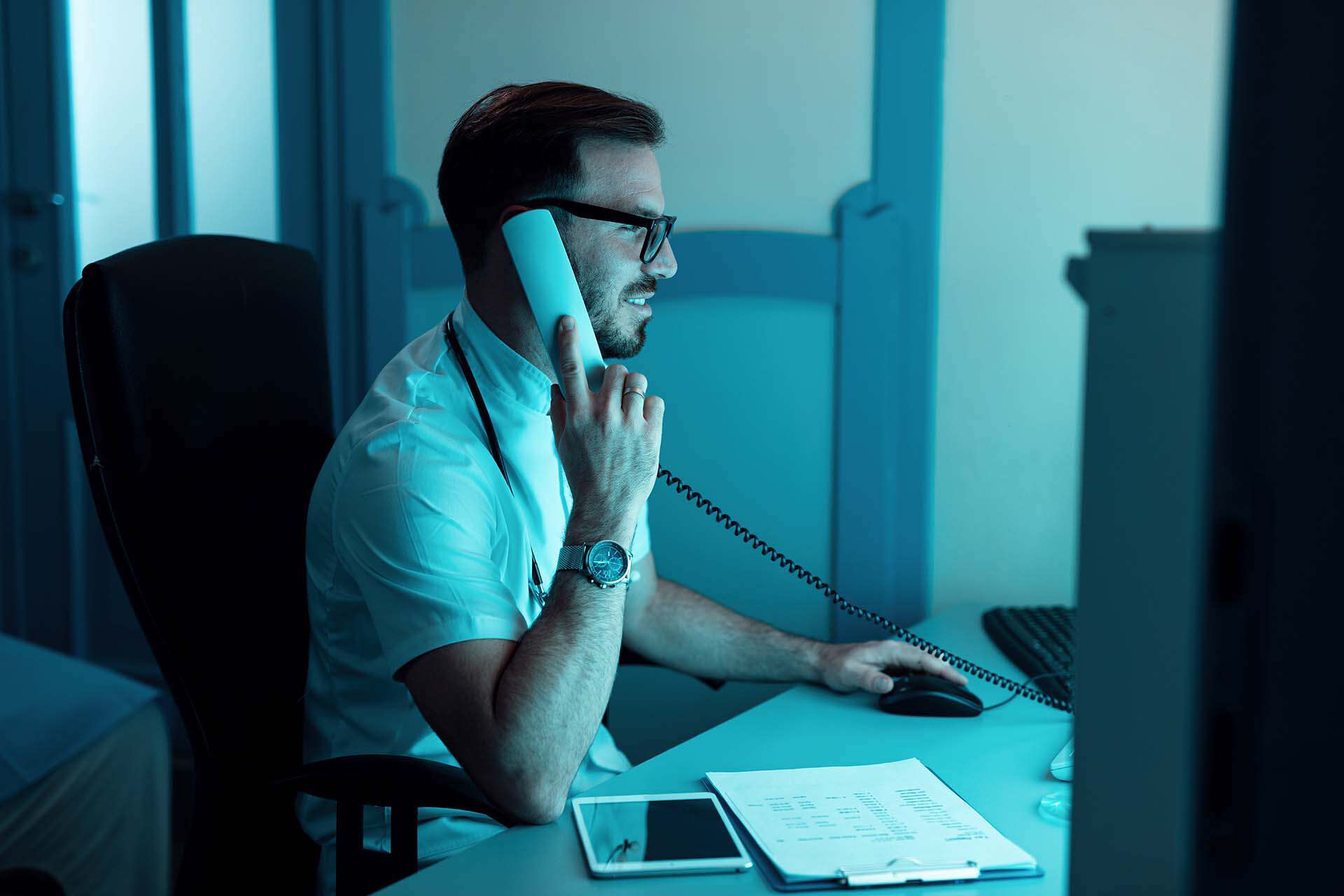 IT professional using phone and computer in office environment.
