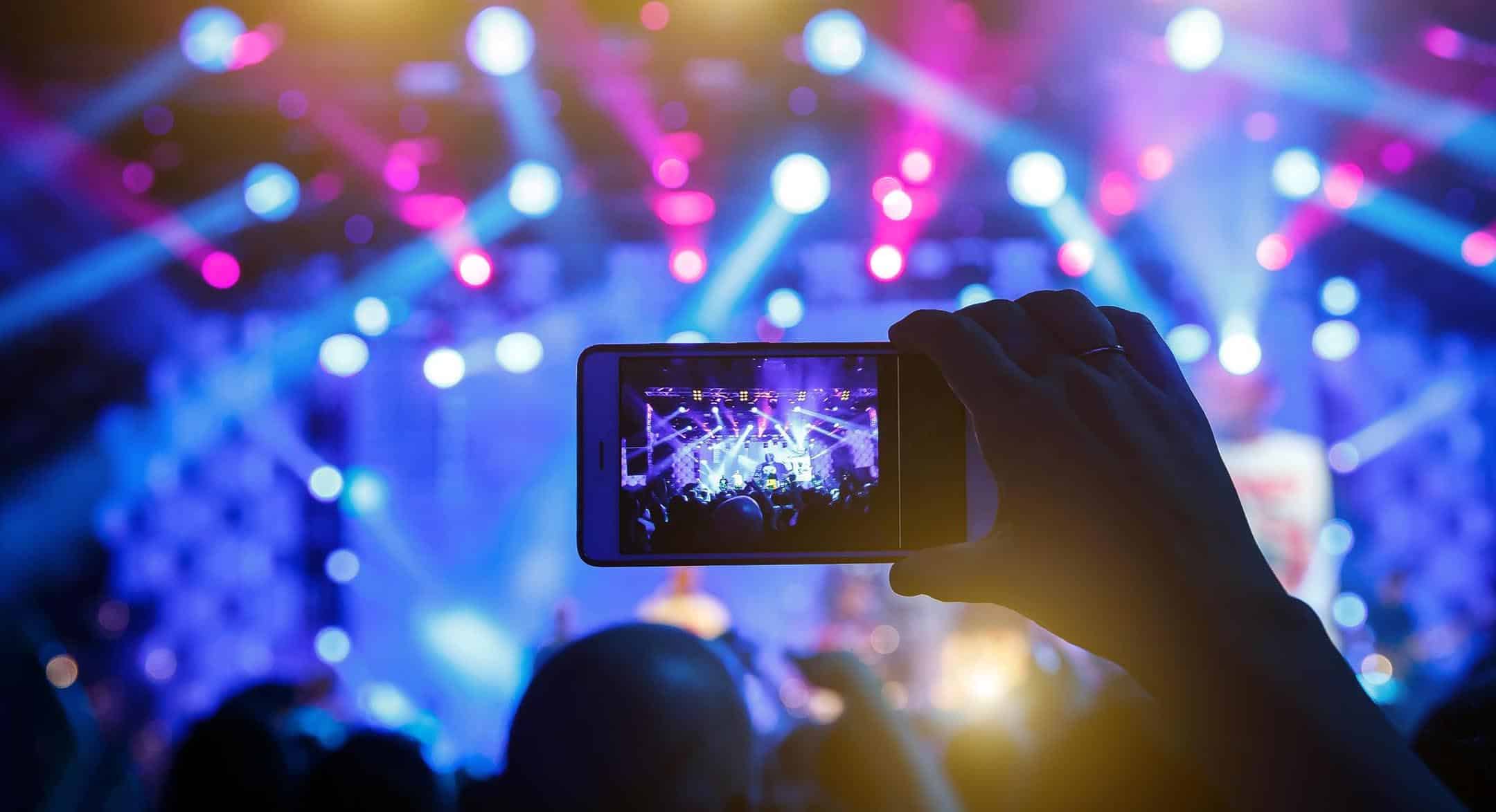 Person recording a concert with a smartphone at a lively event.