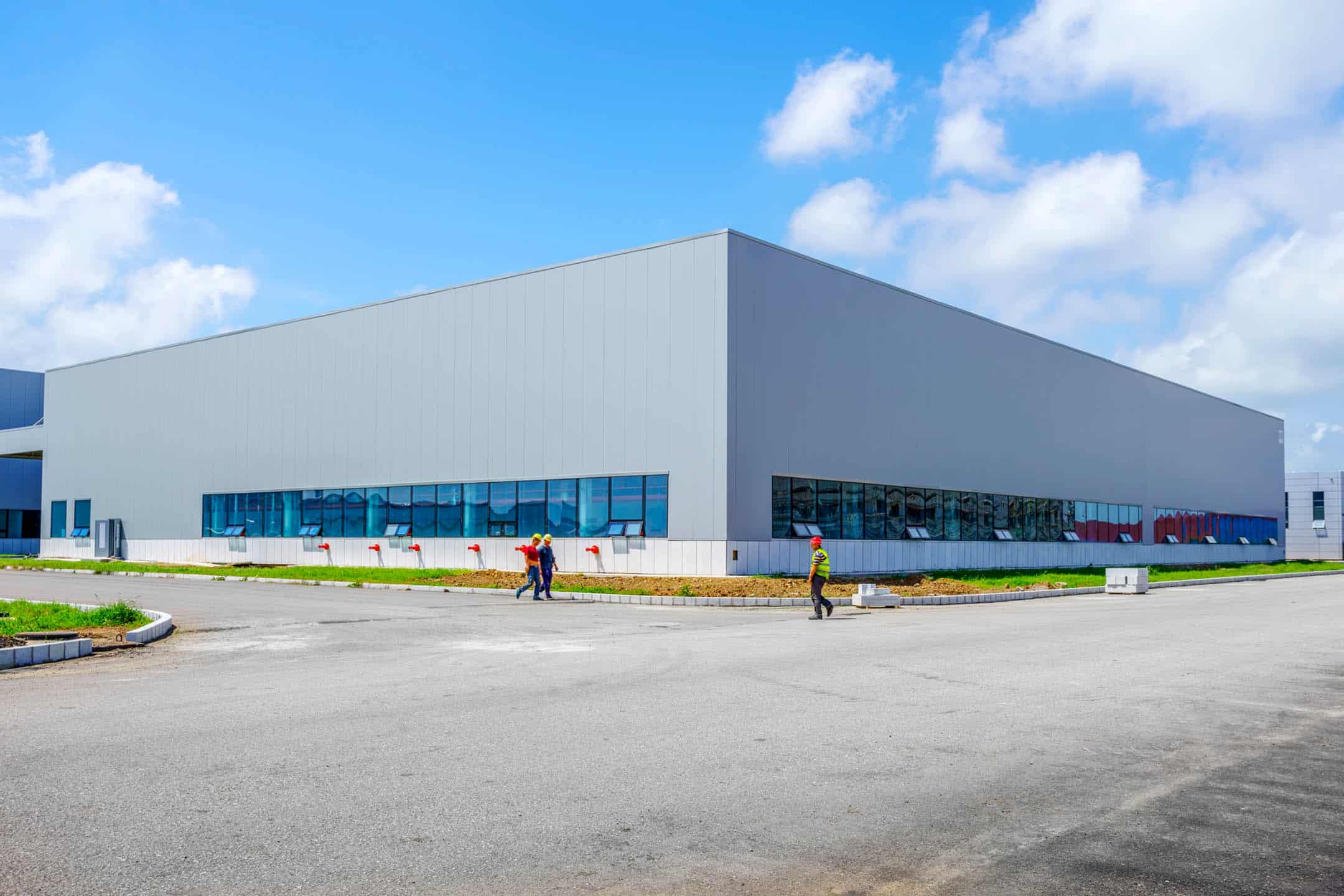 Large industrial warehouse with blue-tinted windows under a blue sky.