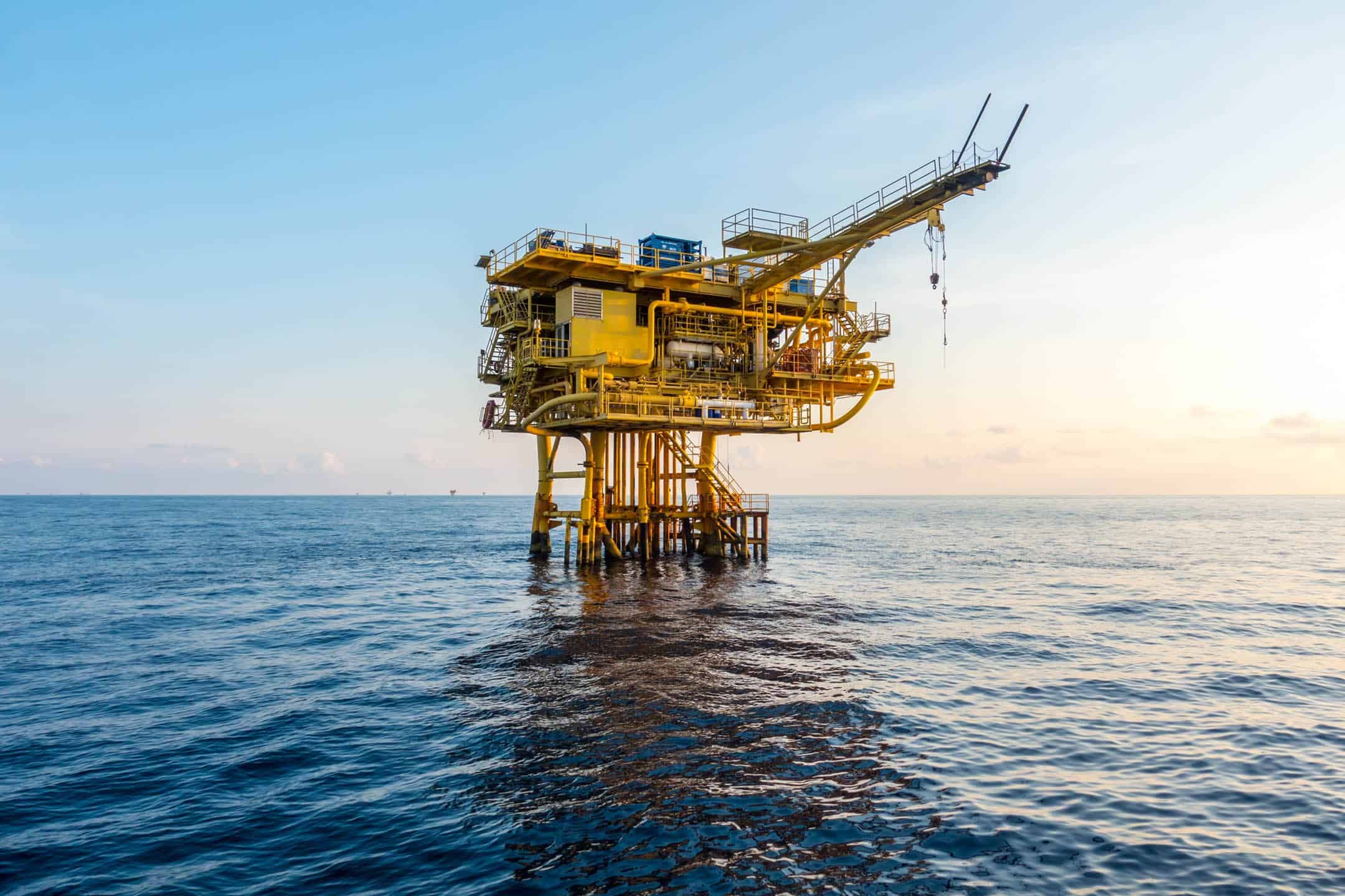 Offshore oil platform in the ocean during sunset.