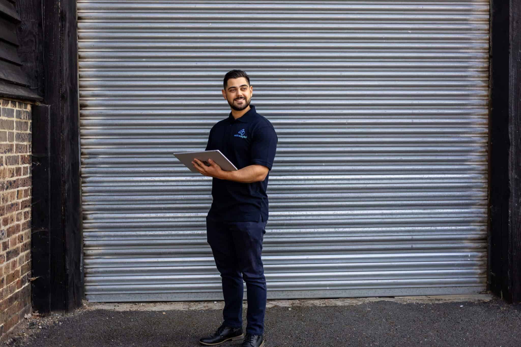 Active Digital technician holding a tablet outside a warehouse.