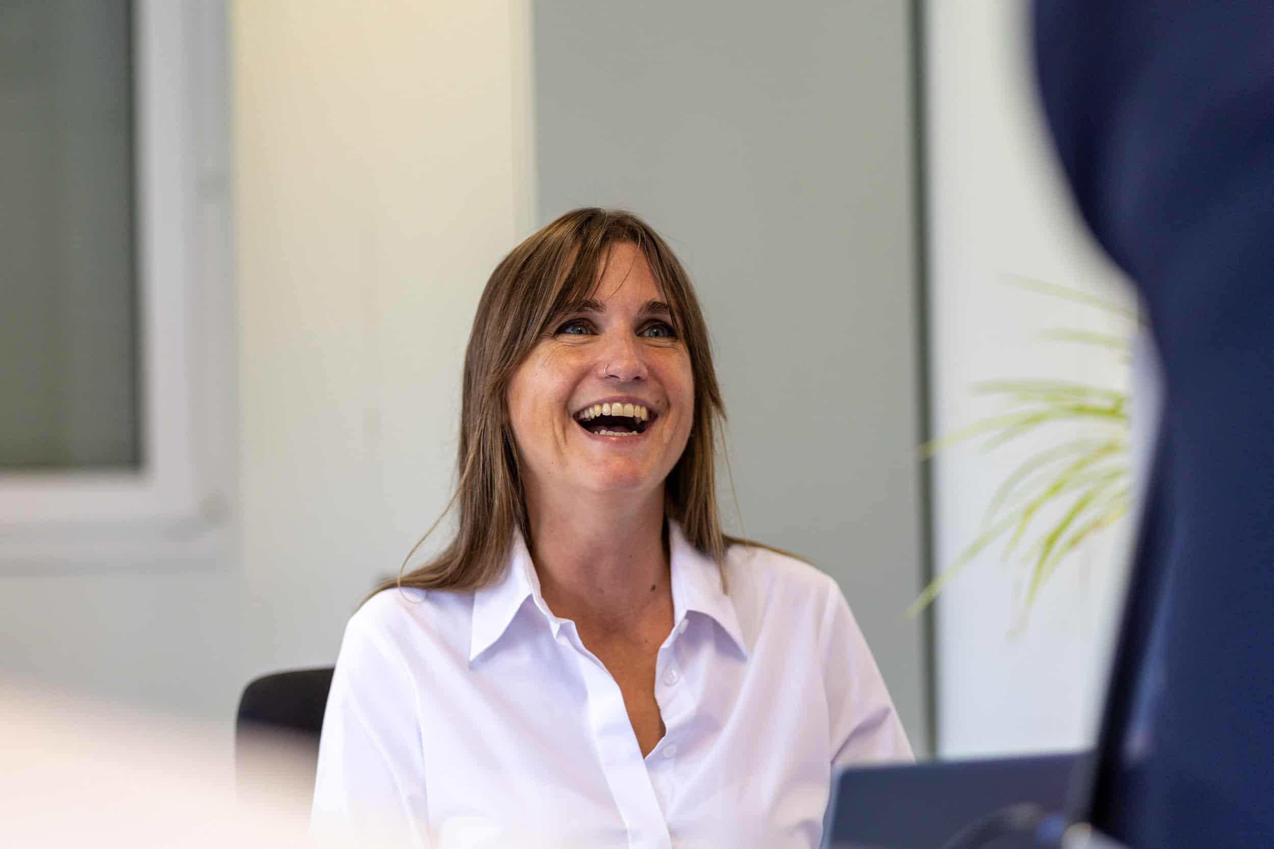 Smiling woman in business attire during a meeting in an office.