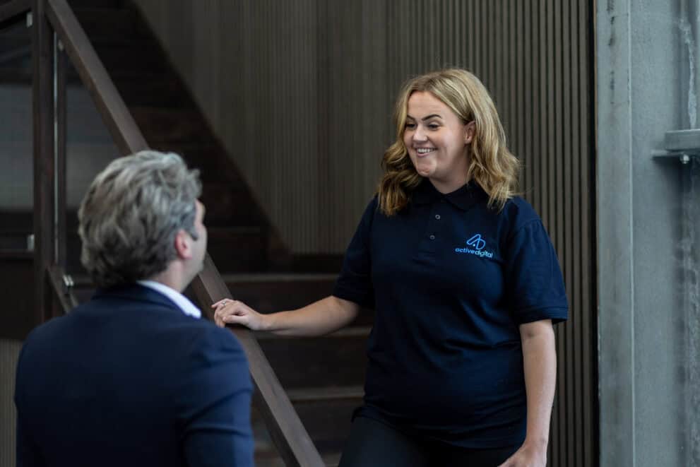 Smiling woman in Active Digital uniform talking to a client.